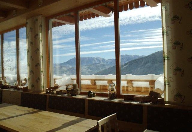 View from a window of snow-covered mountains and blue sky.
