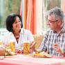 A man and a woman are sitting at a table in a restaurant talking. There are drinks and bread on the table.