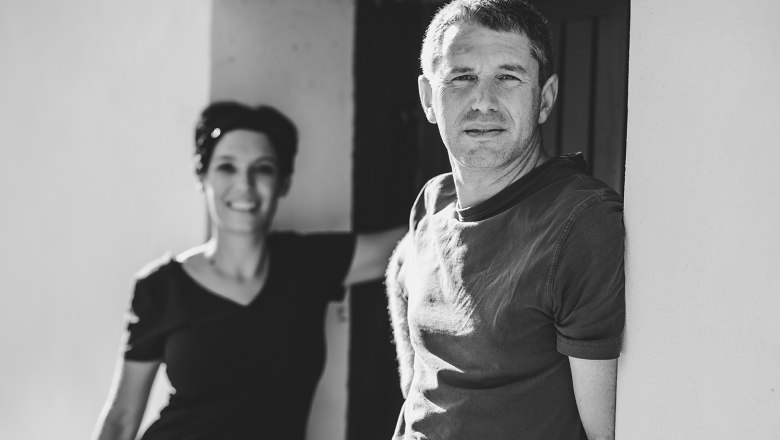 Black and white photo of two people with wine bottles in front of a door.