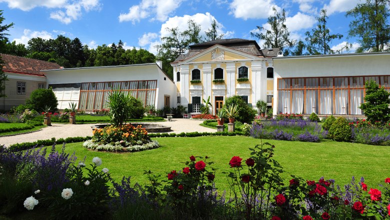 Orangery of Zwettl Abbey with well-tended garden and blooming flowers.