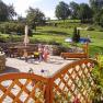Garden with terrace, playground and green meadow in the background.