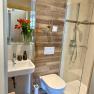 Modern bathroom with shower, washbasin, toilet and flowers.