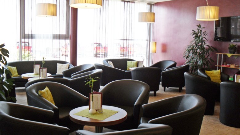 Modern lounge with black armchairs, round tables and large windows.