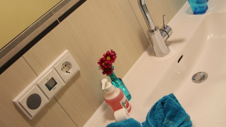 Washbasin with blue towel, soap dispenser and vase with flowers.