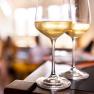 Two wine glasses with white wine on a table, blurred background.