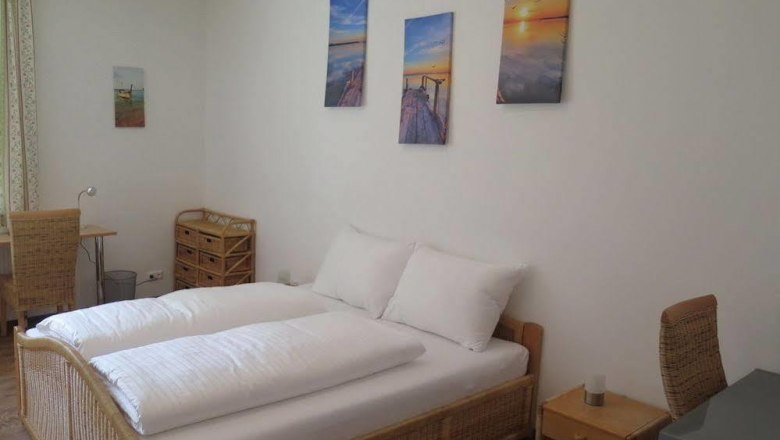 Bright bedroom with double bed, rattan furniture and murals.