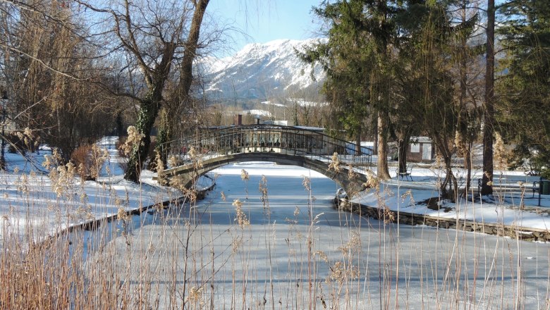 Snow-covered landscape with frozen river and bridge in Reichenau.
