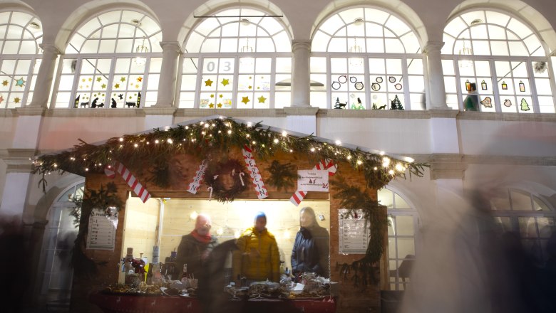 Christmas-decorated punch stand with lights and people in front of it, Katzelsdorf Castle in the background
