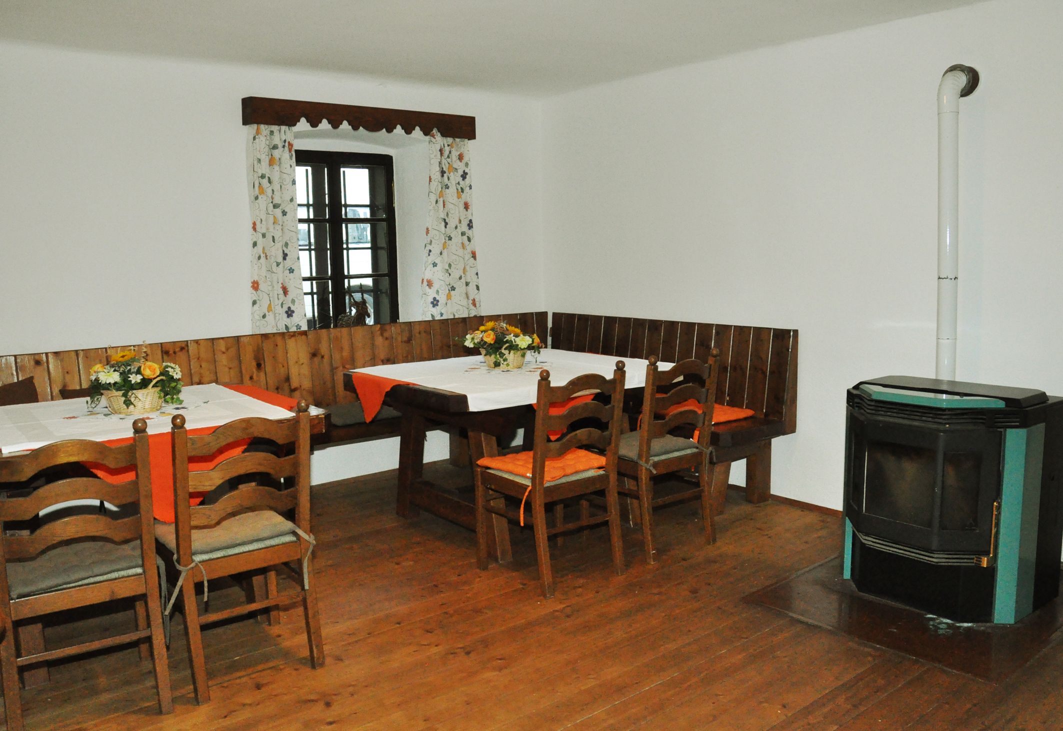 Cozy dining area with wooden table, chairs, corner bench and stove.