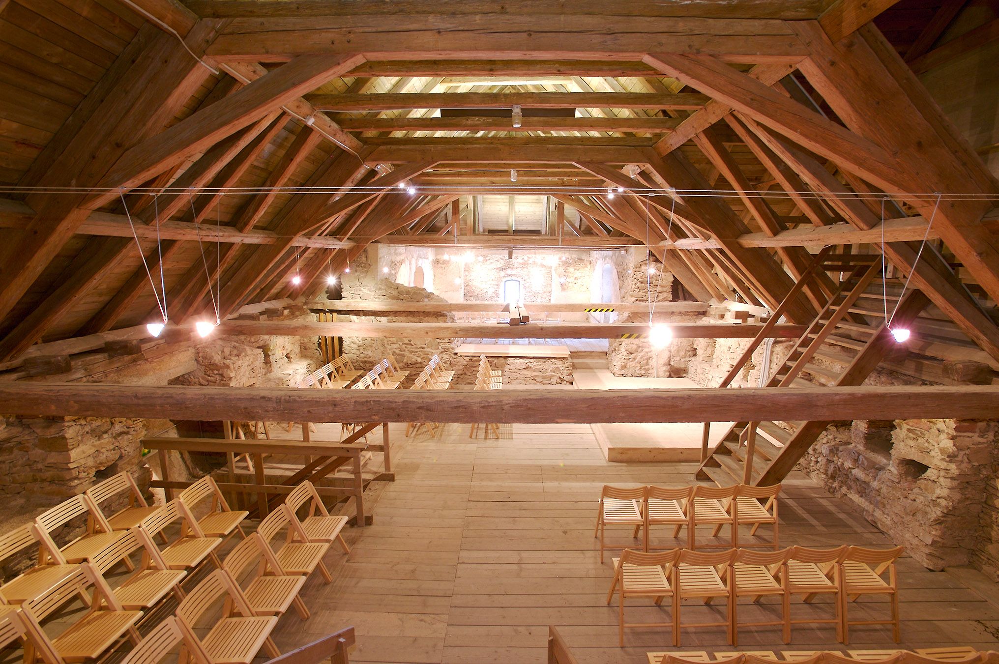 Interior view of the historic attic of the church with wooden beams and chairs.