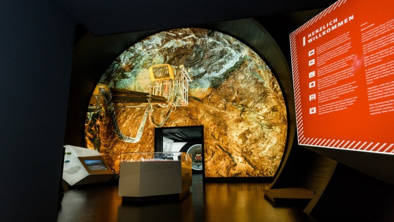Interior view of the Gloggnitz info box with a large projection of a tunnel and an information board.