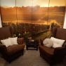 Two brown armchairs with cushions in front of a wall with a landscape photo wallpaper of a vineyard.