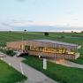 Modern building surrounded by vineyards at sunset.