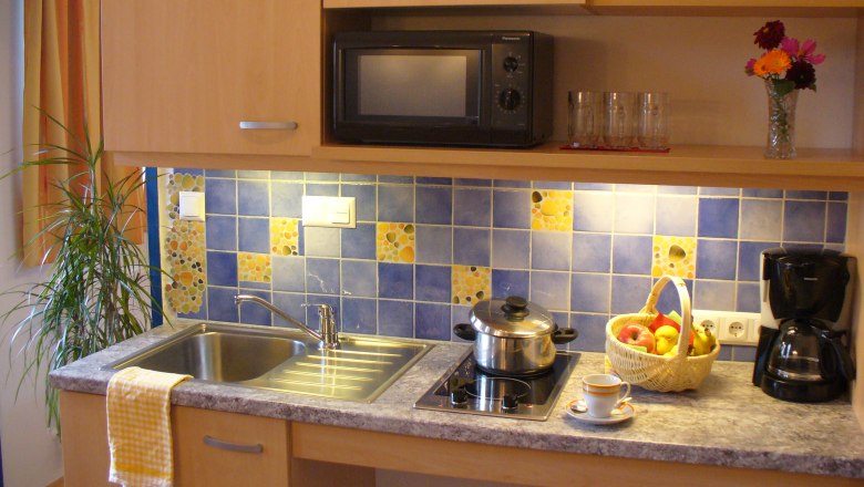 Kitchenette with sink, stove, microwave and decorations.