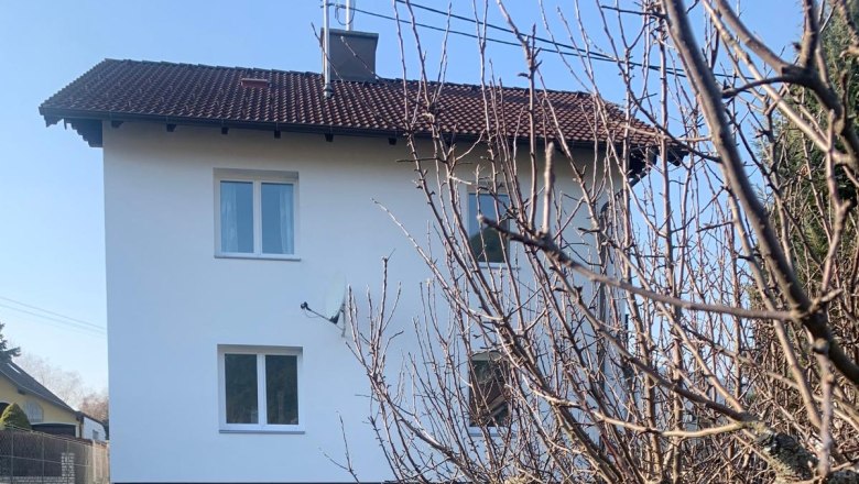 Exterior view of a white house with a red roof and garden.
