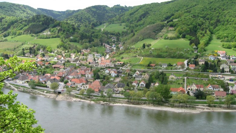 Aerial view of Aggsbach with river and green hills in the background.