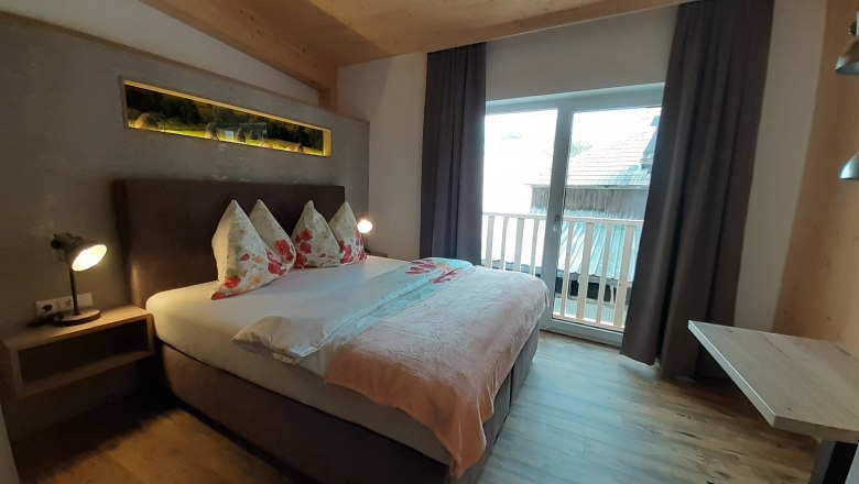 Cozy bedroom with double bed, wooden floor and balcony.