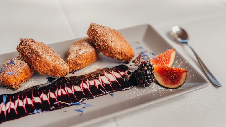 Baked semolina with elderberry sauce, figs and blackberries on a plate.