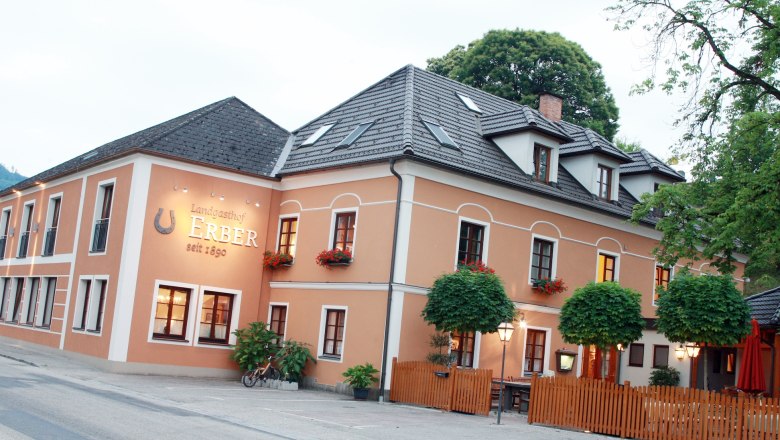 Exterior view of the Landgasthof Erber with orange facade and flower boxes.
