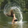 Woman throws her hair back in the water, creating a splash of water.