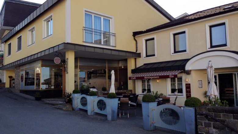 Yellow building with café and terrace, Schüller lettering visible.