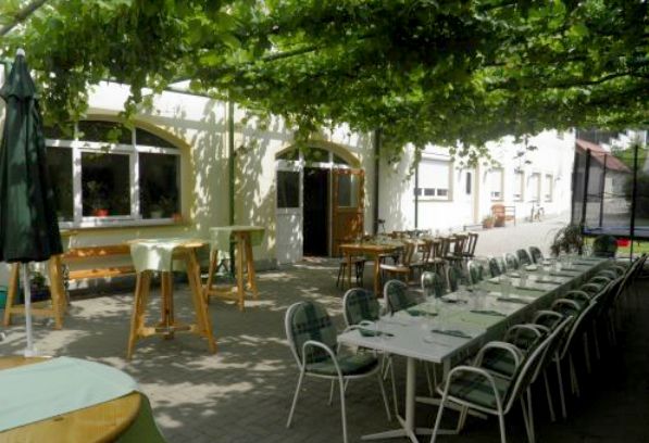 An outdoor area with long tables and chairs under a green canopy.