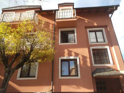 Exterior view of a three-storey house with an orange façade and white window frames.