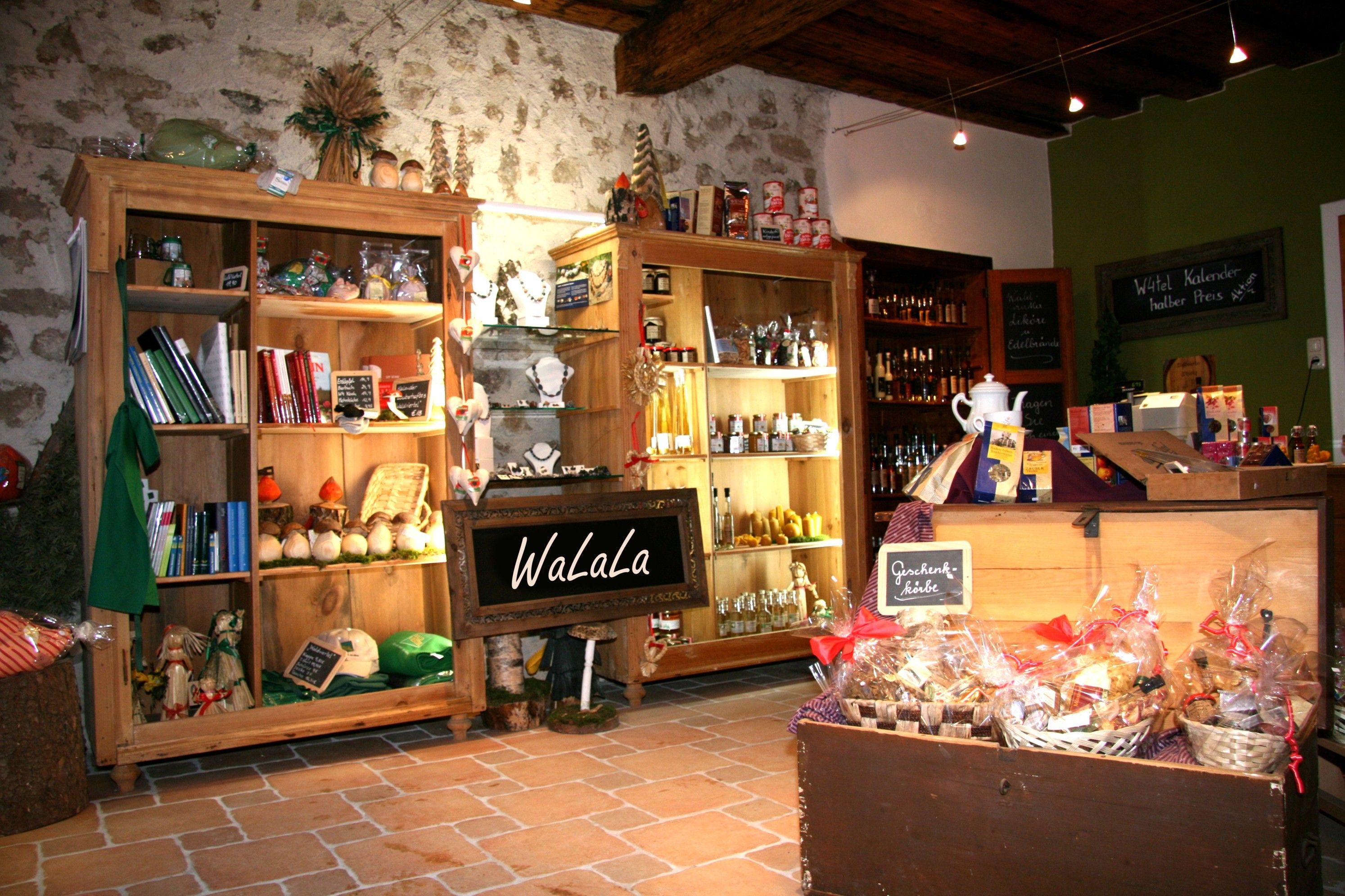 A cozy store with wooden shelves displaying various products and gifts. A sign with the inscription 'WaLaLa' is visible.