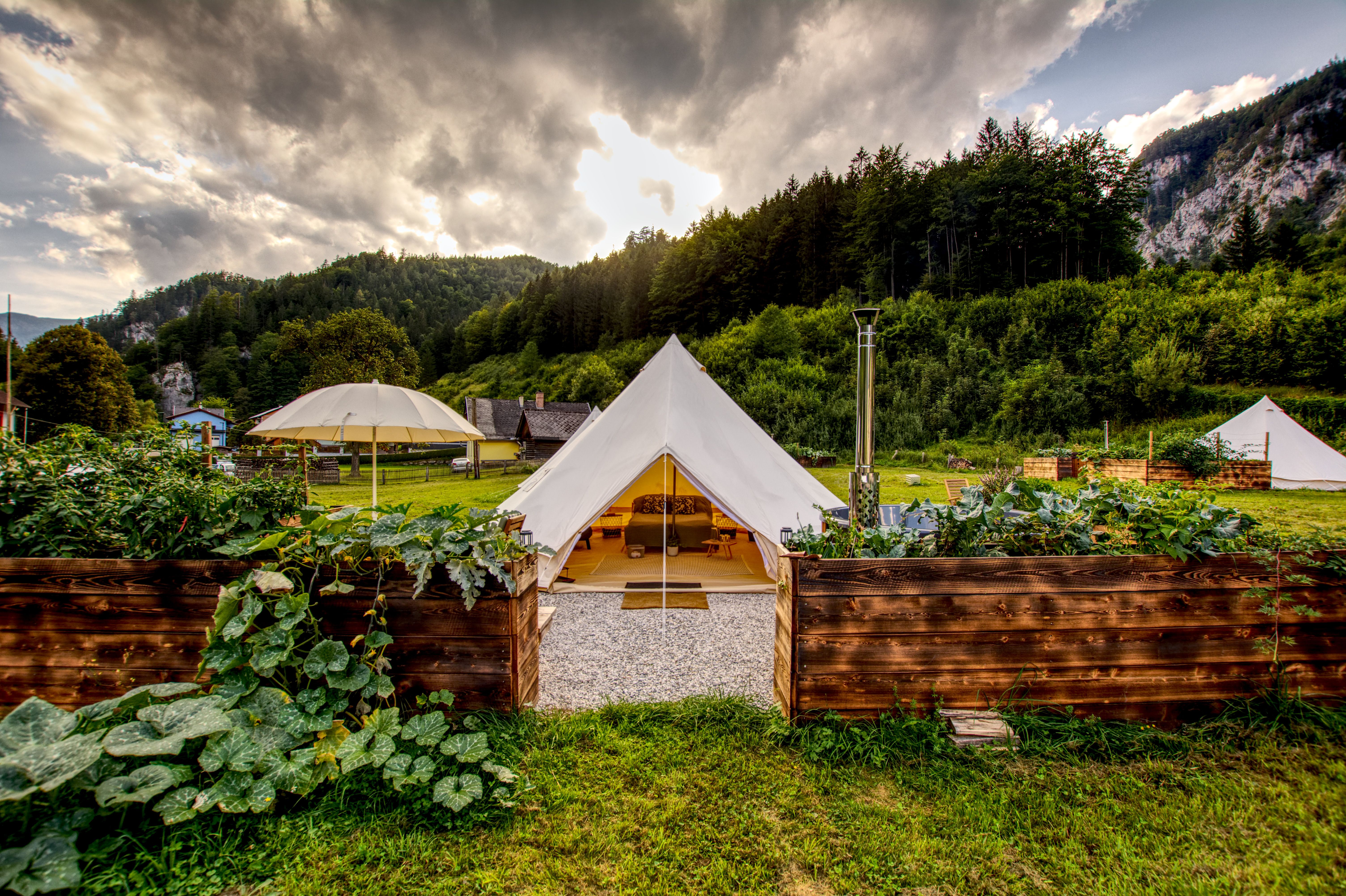 Glamping tent in a green landscape with mountains in the background.