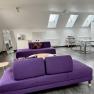 Modern loft with purple sofas, dining table and skylights.