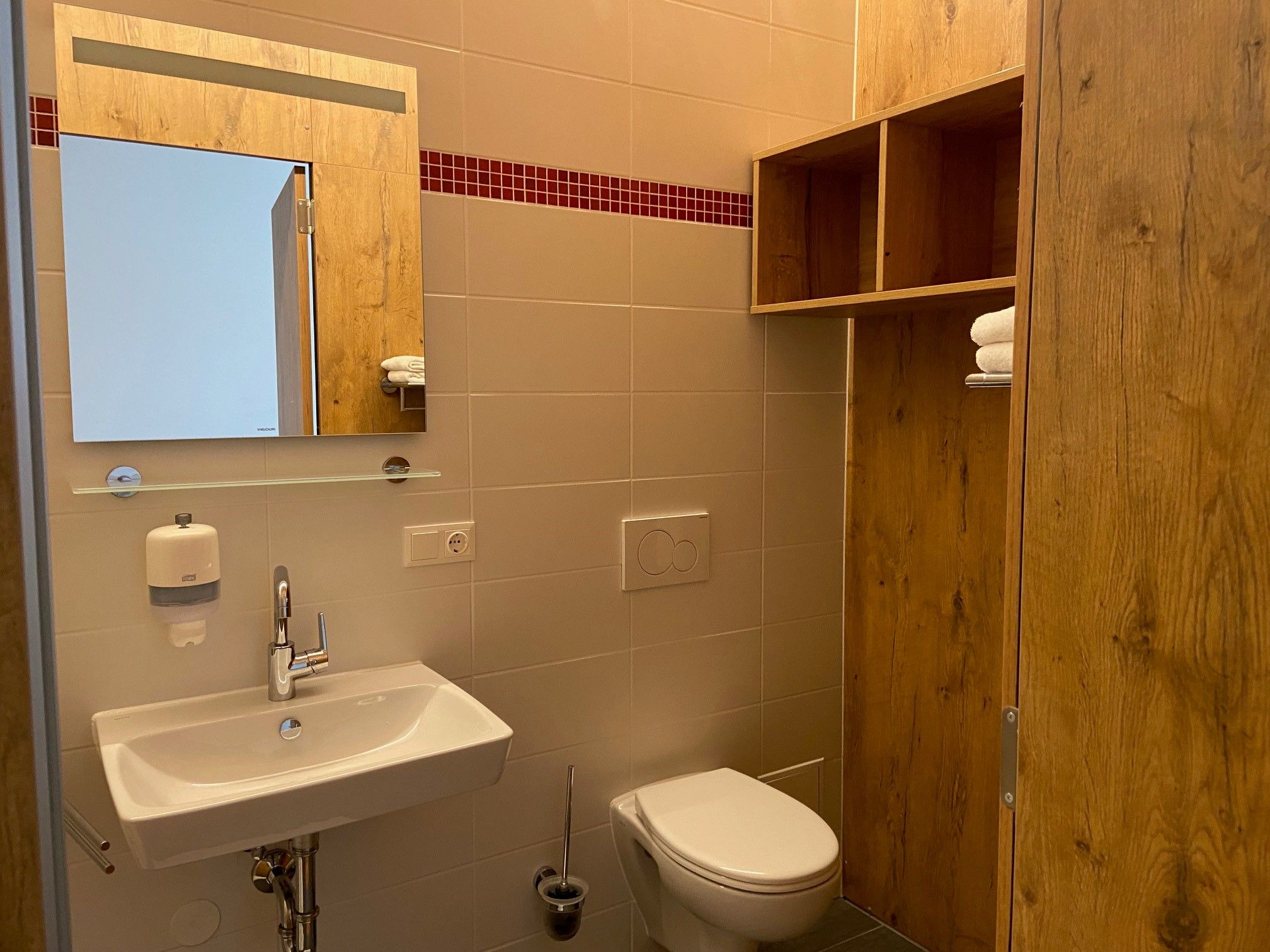 Modern bathroom with washbasin, mirror, WC and wooden shelf.