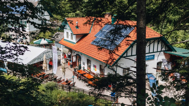 A traditional inn with solar panels on the roof, surrounded by trees.