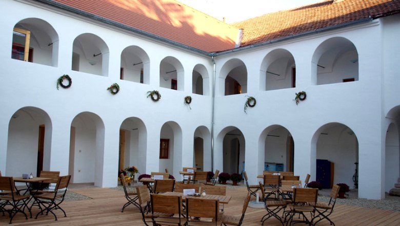 Wolfsbane House, © Wolfgang Rieder Inner courtyard of the Eisenhuthaus with arcades and wooden furniture.