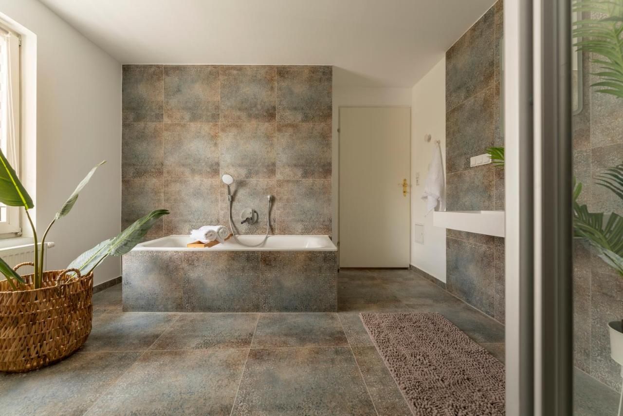 Modern bathroom with bathtub, plants and towel.