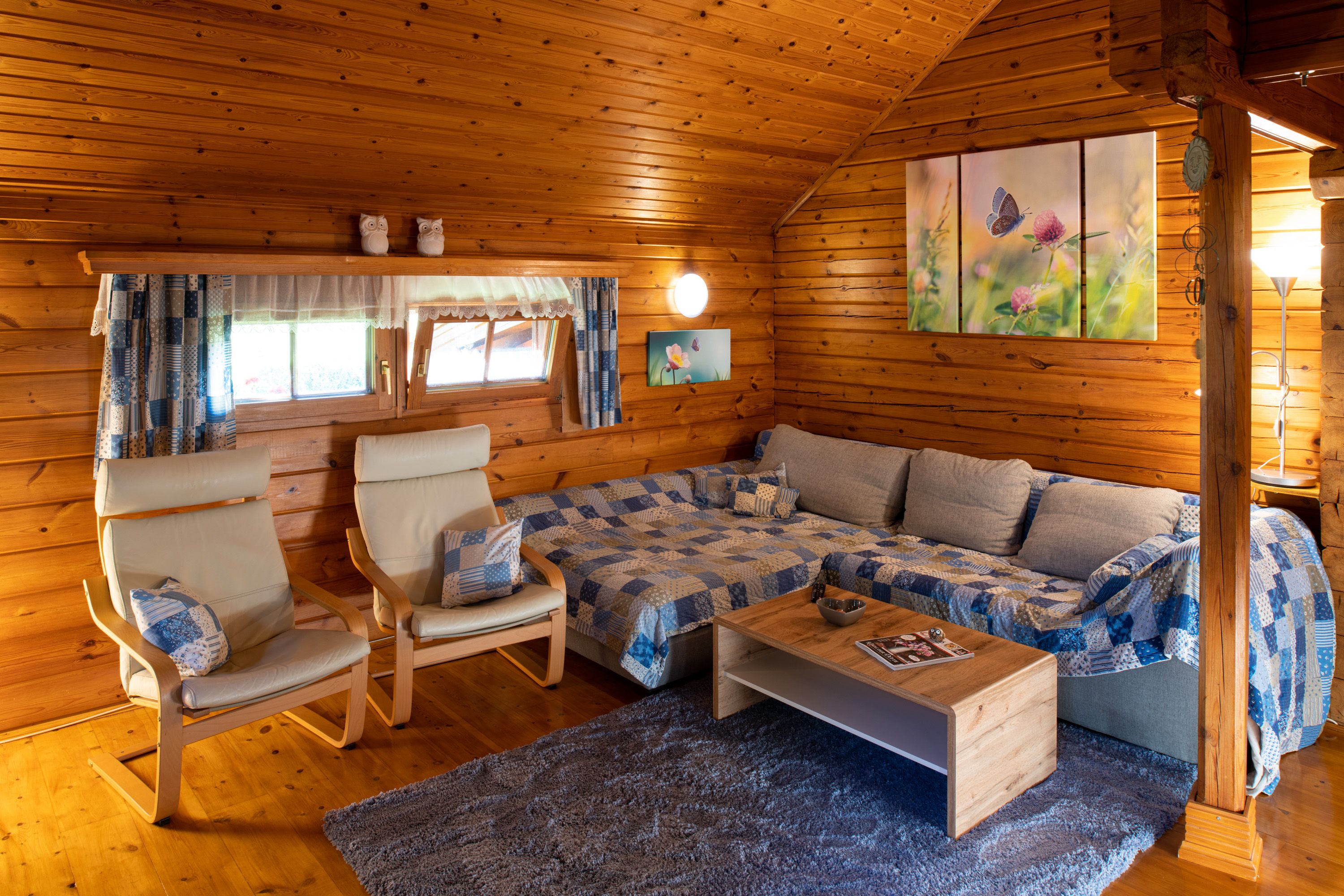 Cozy living room in a wooden hut with sofa, armchairs and decoration.