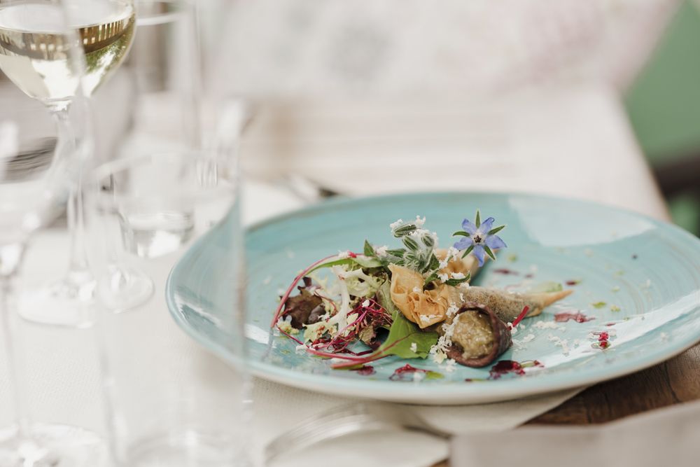 A plate with Blunzenspitz, melanzani caviar and lettuce, decorated with edible flowers.