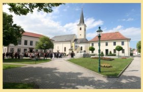 Absdorf parish church with surrounding square and gathering of people.