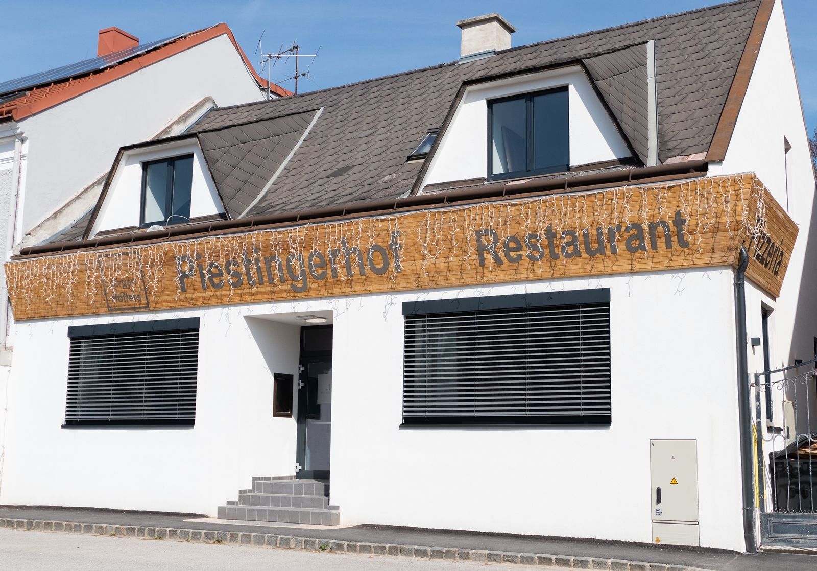 Façade of a restaurant called Piestingerhof, decorated with fairy lights.