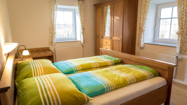 Comfortable bedroom with wooden furniture and colorful bed covers.