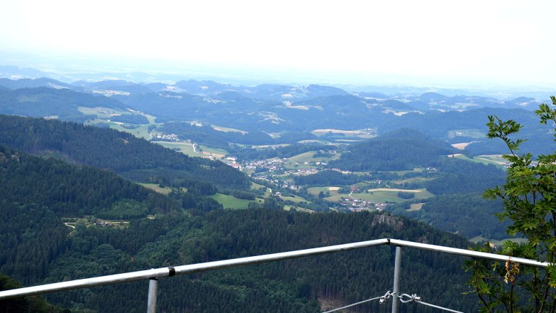 View from the castle stone wall of a hilly landscape with forests and villages.