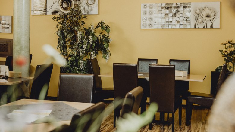 Cozy restaurant with yellow walls, plants and modern art.
