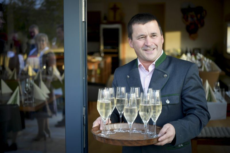 A man in traditional dress serves champagne glasses on a tray.