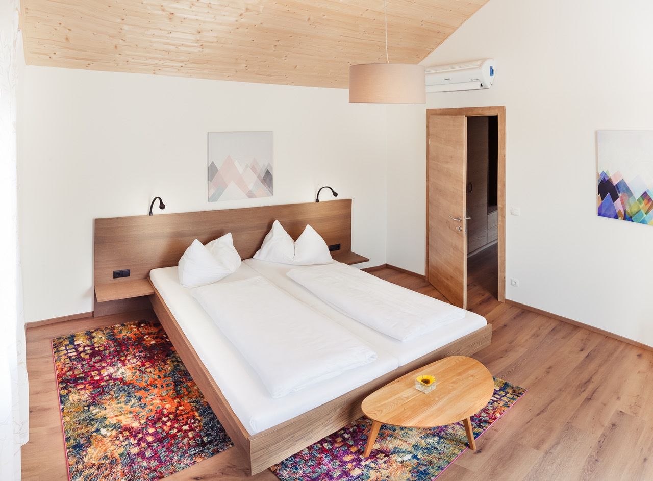 Modern bedroom with double bed, wooden furniture and colorful carpet.