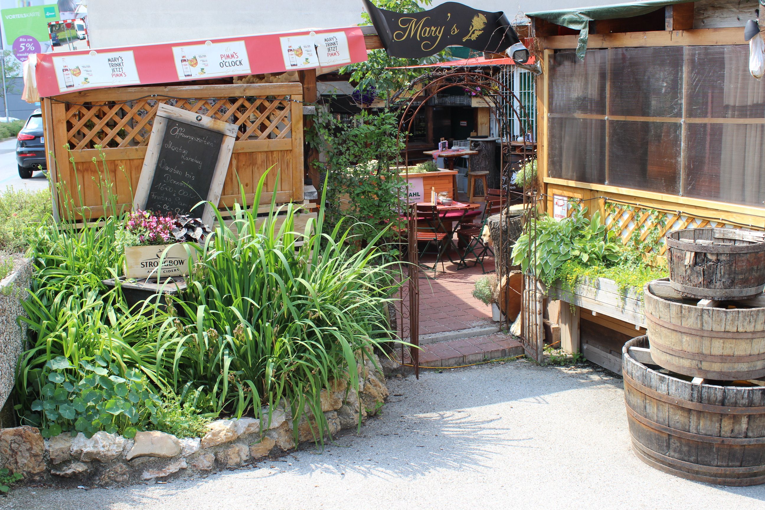 Entrance to a cozy pub garden with wooden tables and plants.