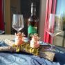 Wine bottle with two empty glasses and decorative figures on a table.