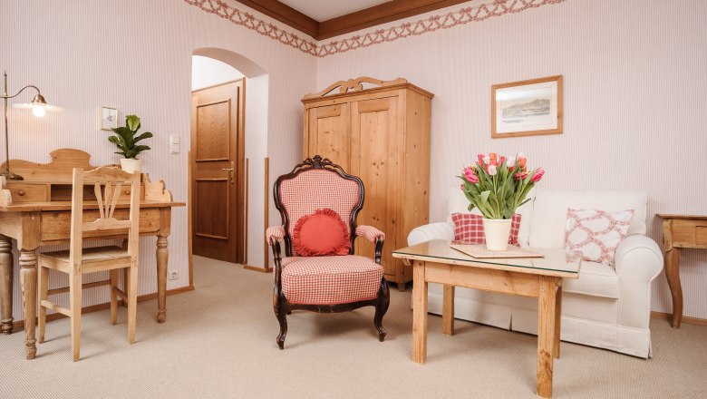 Cozy living room with wooden furniture, an armchair, sofa and table with tulips.