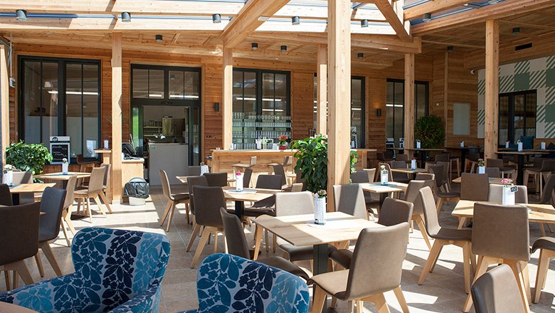 A modern coffee house with lots of wooden elements, angular tables and brown and blue chairs.
