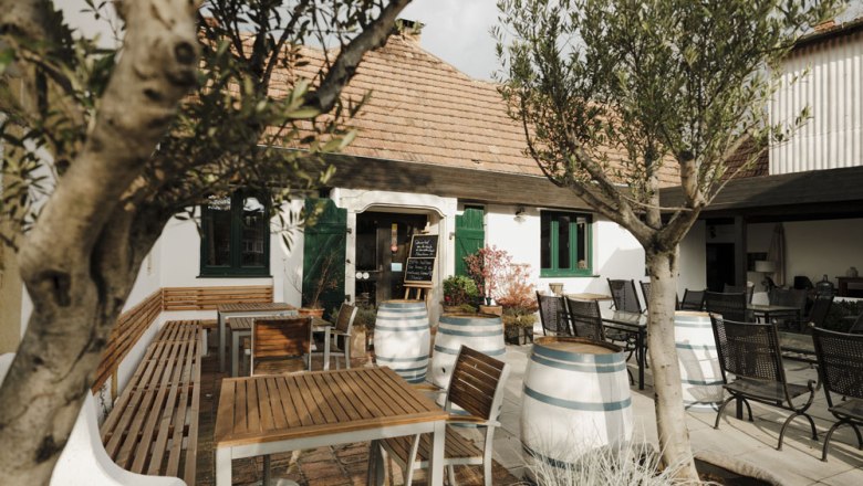 Cozy courtyard with wooden tables, wine barrels and olive trees.
