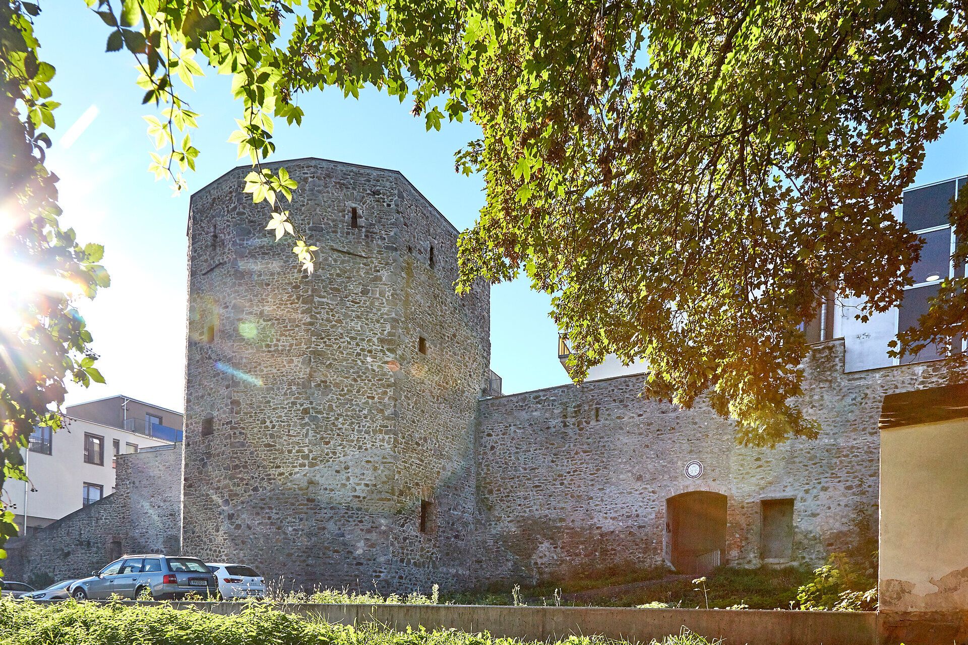 Town wall and tower in Waidhofen an der Thaya, surrounded by trees and sunlight.