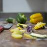 Vegetables and knives on a chopping board in a kitchen.